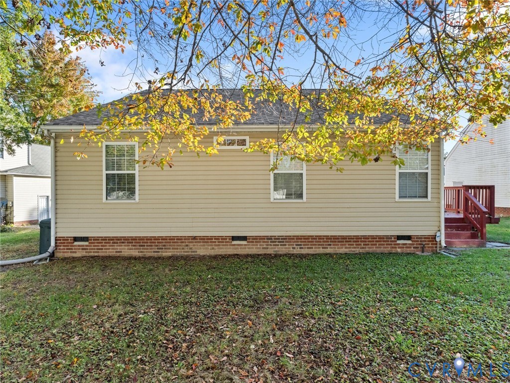 Exterior featuring neutral-tone horizontal siding, a brick foundation, three windows, and a raised wooden deck