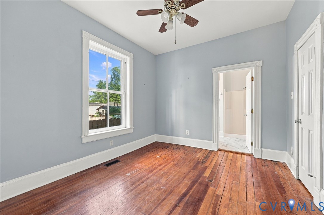1st floor bedroom : Interior space featuring natural wood-finish flooring, white paneled doors with traditional millwork, and a built-in knee-wall access door