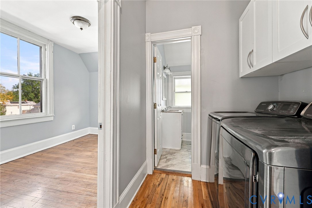 2nd Floor Laundry space featuring wood-finish flooring, white upper cabinetry, and traditional architectural trim