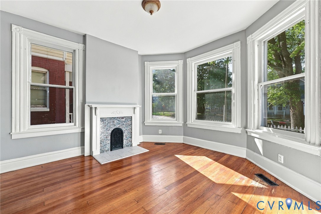 Hardwood flooring, fireplace with decorative surround and mantle, and bay window configuration with multi-pane windows and traditional millwork trim Hardwood flooring, fireplace with decorative surround and mantle, and bay window configuration with multi-pane windows and traditional millwork trim