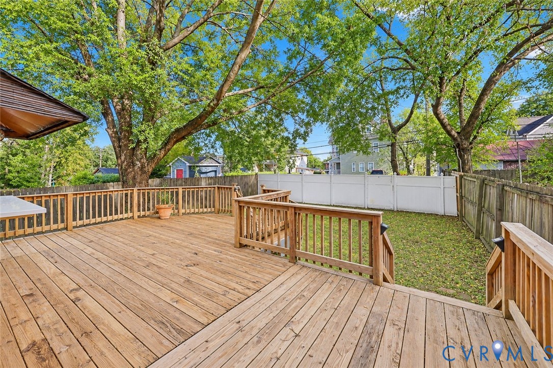Multi-level wood deck featuring built-in railings, privacy fencing, and mature trees Multi-level wood deck featuring built-in railings, privacy fencing, and mature trees