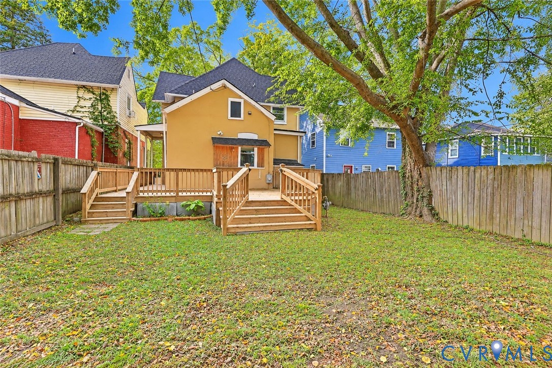 Backyard featuring a raised wooden deck with railings, wooden privacy fencing, and mature trees Backyard featuring a raised wooden deck with railings, wooden privacy fencing, and mature trees