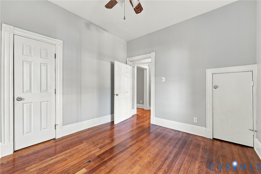 1st floor bedroom : Interior space featuring natural wood-finish flooring, white paneled doors with traditional millwork, and a built-in knee-wall access door