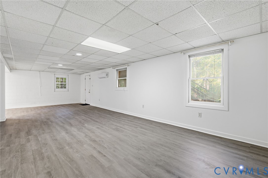 Open-concept interior featuring wood-finish flooring, a suspended drop ceiling, recessed lighting, and a wall-mounted ductless climate control unit