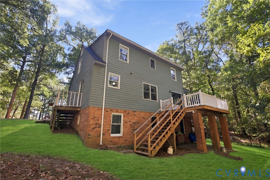 Exterior featuring horizontal siding, a brick foundation, elevated wood deck with white railings, and a wooded lot