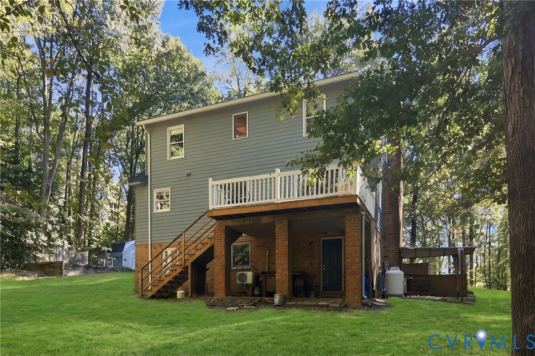 Exterior featuring a multi-level structure with a raised deck, brick-column foundation, wood-framed staircase, and light-tone siding