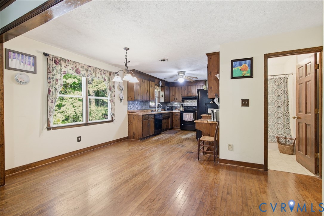Kitchen area featuring wood cabinetry, wood flooring, a multi-light chandelier, and a six-panel wooden door Kitchen area featuring wood cabinetry, wood flooring, a multi-light chandelier, and a six-panel wooden door