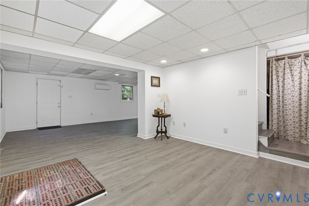 Finished interior space featuring wood-finish flooring, a drop ceiling with recessed lighting, a ductless mini-split system, and a single-panel door