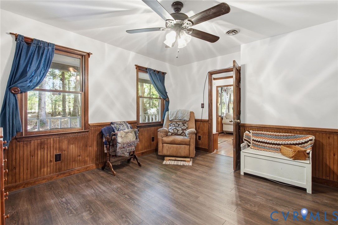 Interior space featuring wood-finish flooring, wood wainscoting, and a multi-blade ceiling fan with integrated lighting