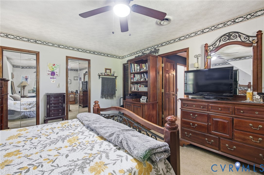 Room featuring dual mirrored closet doors, a built-in wooden shelving unit, and an overhead ceiling fan with integrated lighting
