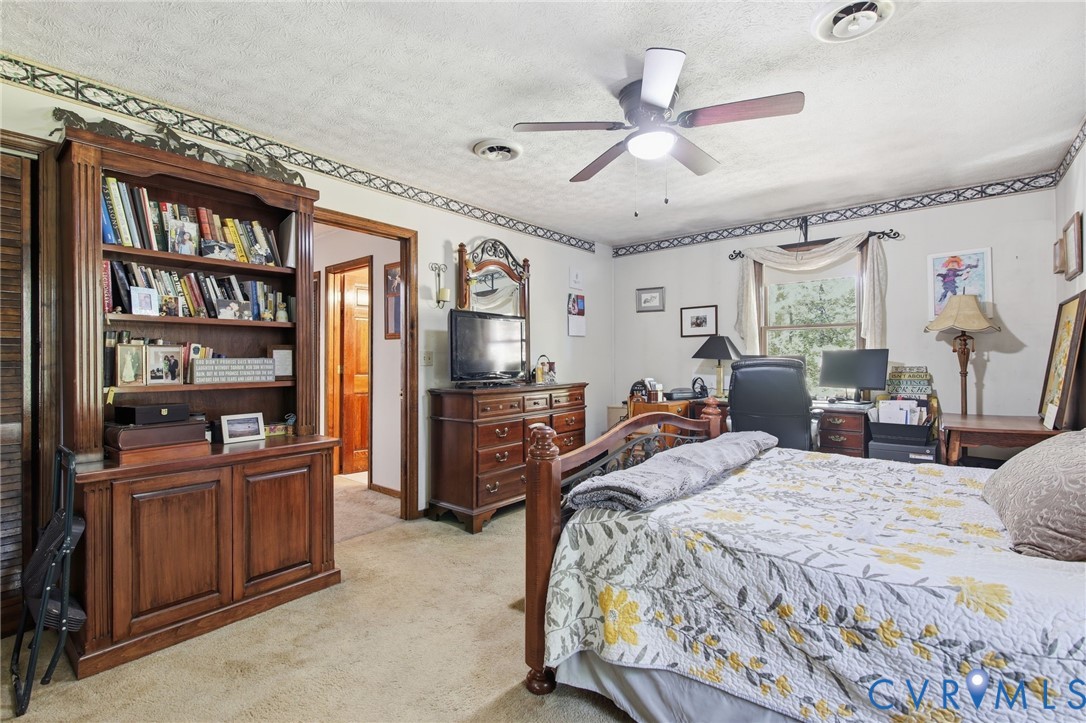 Built-in wooden shelving unit, ceiling fan with light fixture, and window with textile valance