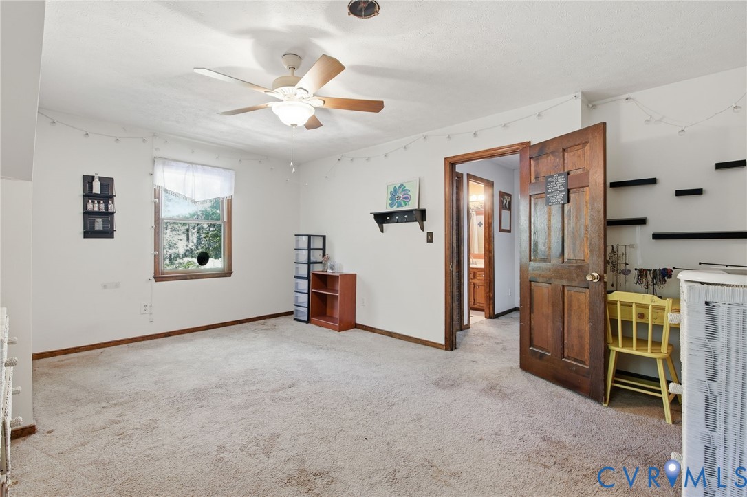 Interior room featuring wall-to-wall carpeting, a ceiling fan with integrated light fixture, a single-hung window, and a solid wood six-panel door