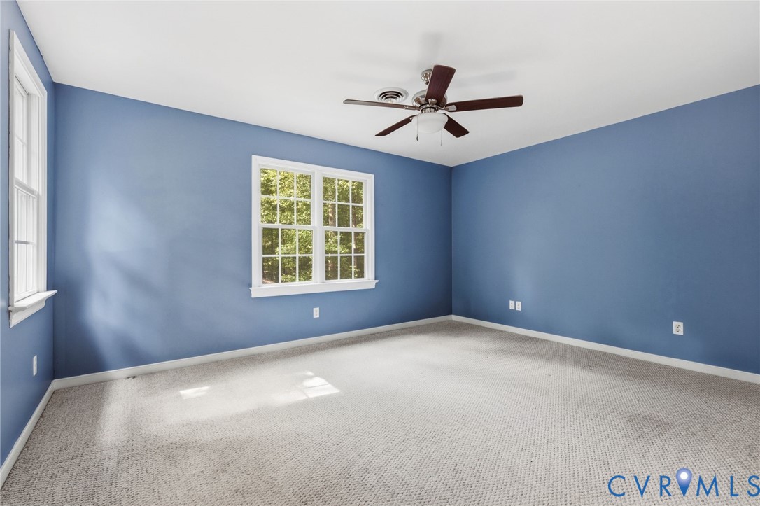 Interior space featuring wall-to-wall carpeting, multiple multi-pane windows, and a central ceiling fan with an integrated light fixture