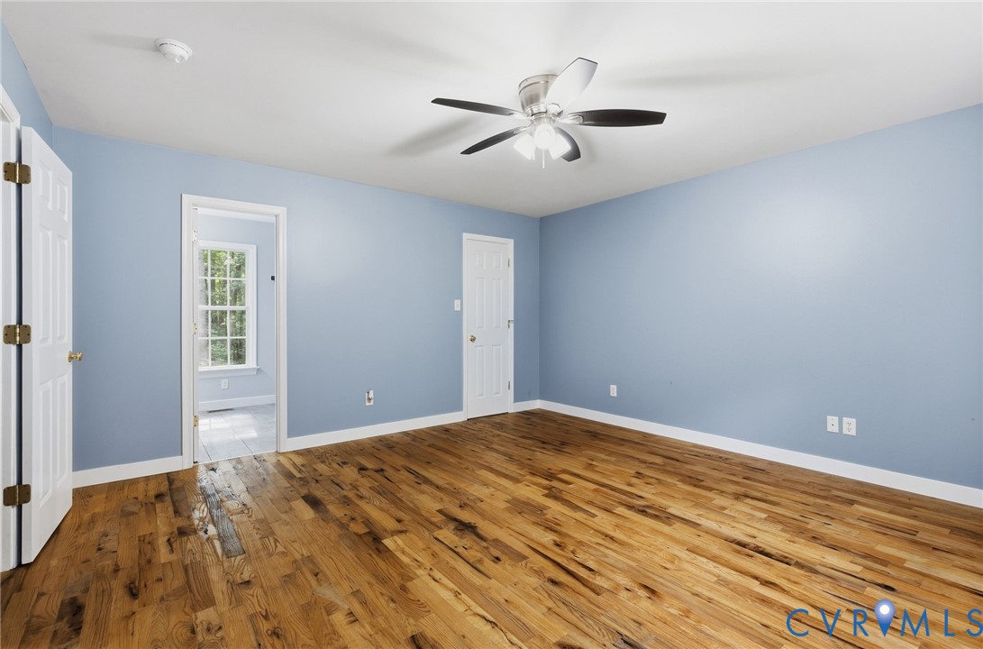 Wood-finish flooring, multi-pane window, and central ceiling fan with integrated lighting