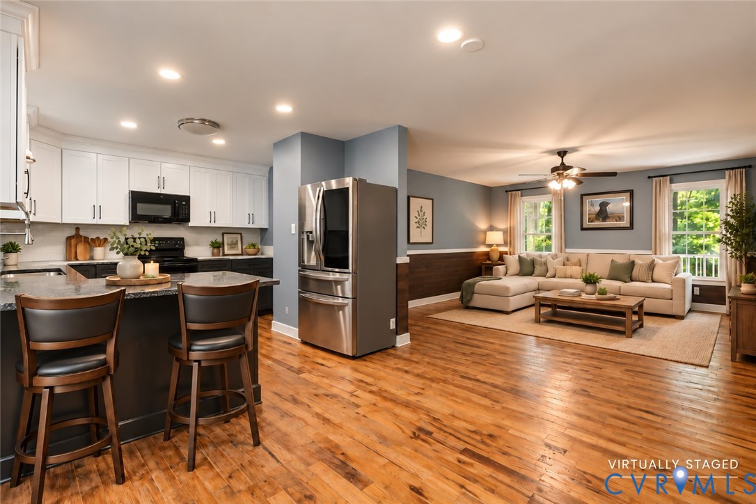 Kitchen featuring shaker-style cabinetry, stone countertops, stainless steel appliances, wood-finish flooring, and recessed lighting Kitchen featuring shaker-style cabinetry, stone countertops, stainless steel appliances, wood-finish flooring, and recessed lighting