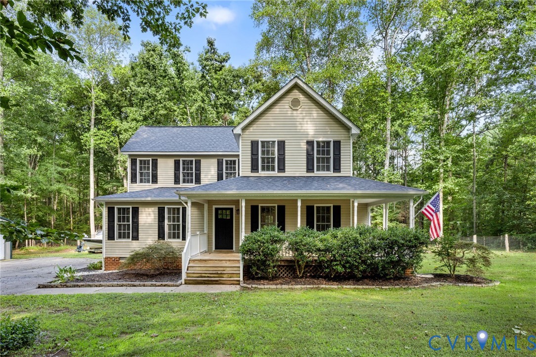 Two-story residence featuring light-toned vinyl siding, a covered front porch, dark-framed multi-pane windows, and a shingled roof Two-story residence featuring light-toned vinyl siding, a covered front porch, dark-framed multi-pane windows, and a shingled roof