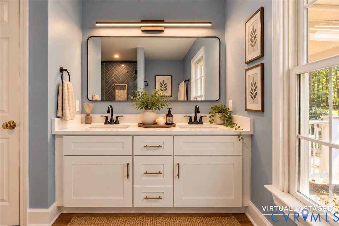 Double vanity featuring white shaker-style cabinetry, solid-surface countertop with dual integrated sinks, matte black widespread faucets, and a large rectangular mirror with a matching matte black frame