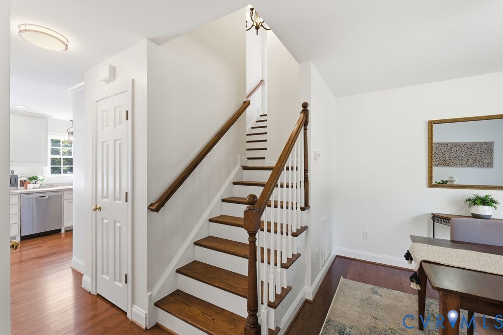 Staircase featuring wood-finish treads, white risers, and a wooden handrail with a decorative newel post