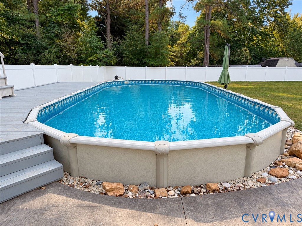 *pictures from summer* Above-ground pool with stone landscaping, gray composite decking, and perimeter vinyl fencing
