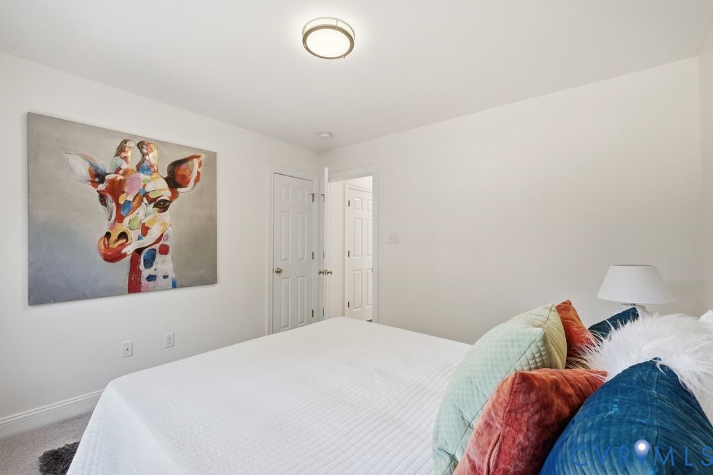 Neutral-toned room featuring wall-to-wall carpeting, a multi-panel interior door, and a flush-mount circular ceiling fixture