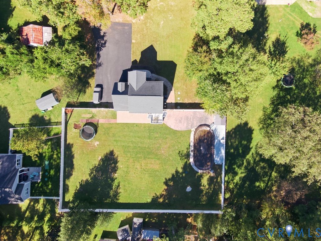 Aerial perspective of a property featuring a fenced backyard, an in-ground pool, a paved patio, and a driveway