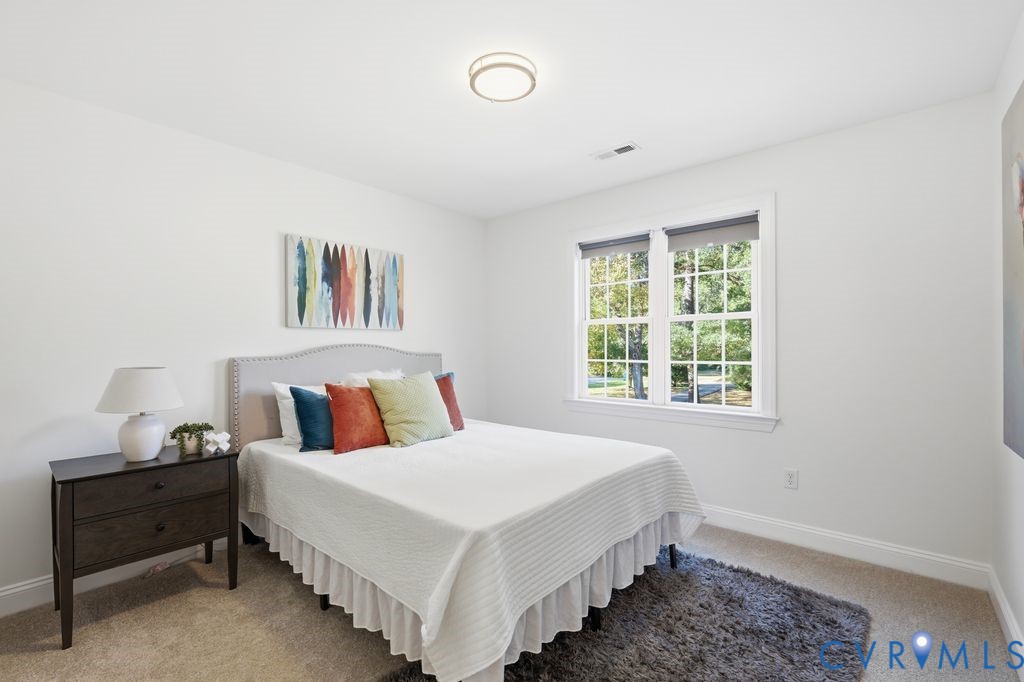 Neutral-toned wall-to-wall carpeting, double-pane grid windows, and circular flush-mount ceiling lighting