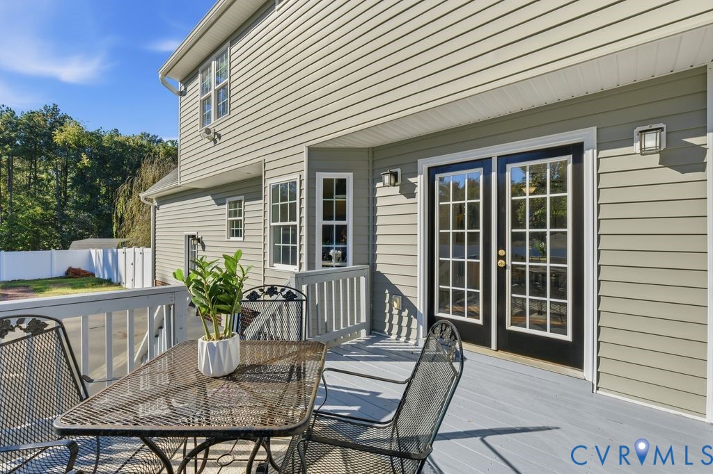 Light-grey elevated deck featuring a white railing and black-framed French doors with glass panes