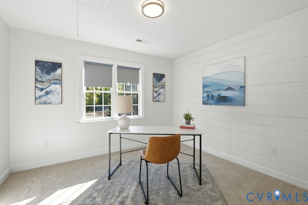Room featuring horizontal shiplap accent wall, neutral carpeting, and a multi-pane window with roller shades, illuminated by a modern flush-mount light fixture