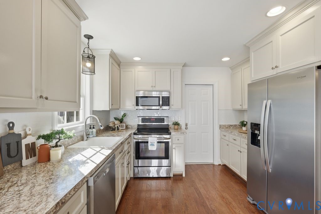 Kitchen featuring off-white cabinetry, stone-patterned countertops, stainless steel appliances, recessed lighting, and wood-finish flooring