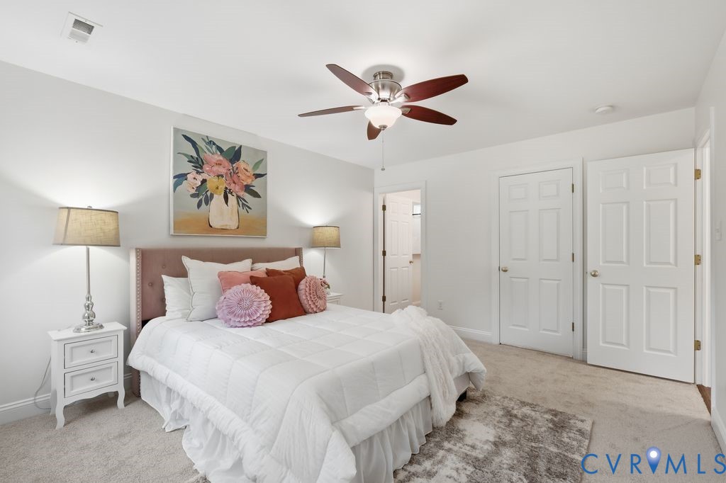 Neutral interior featuring wall-to-wall carpeting, a multi-blade ceiling fan with integrated lighting, and two six-panel interior doors