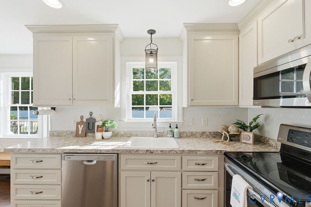 Shaker-style cabinetry, stone-finish countertops, white subway tile backsplash, stainless steel appliances, and a single-basin undermount sink