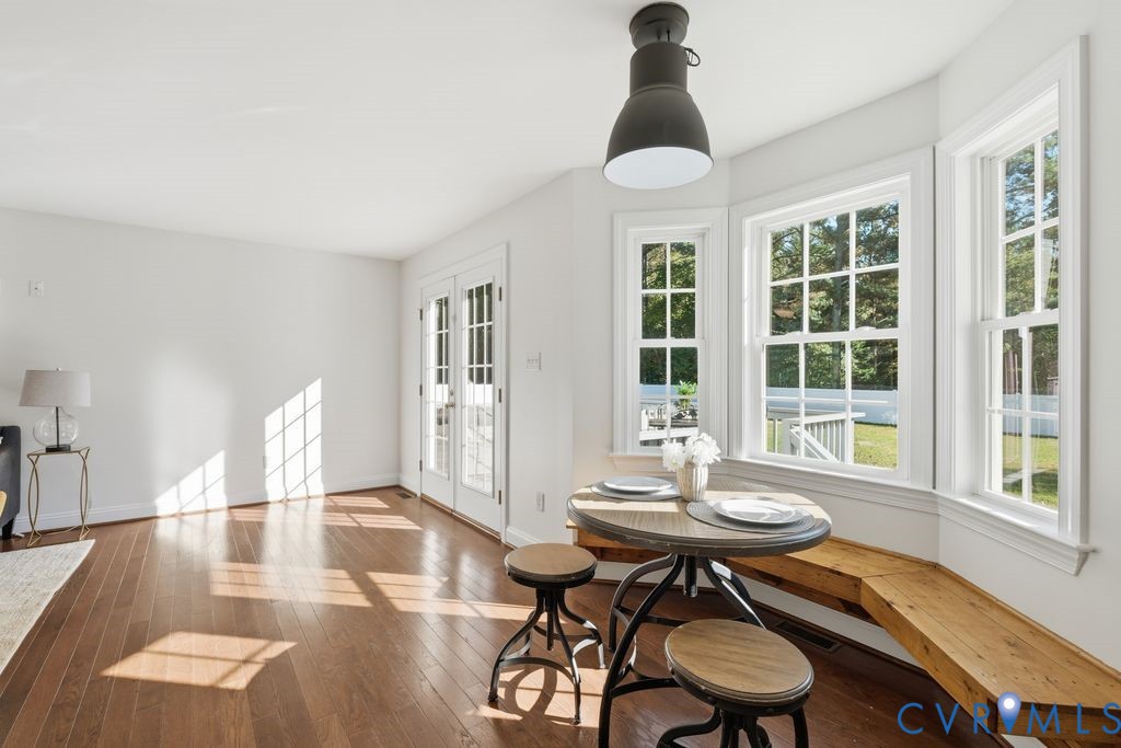 Wood-finish flooring, bay windows with custom built-in bench seating, pendant lighting, and multi-light French doors