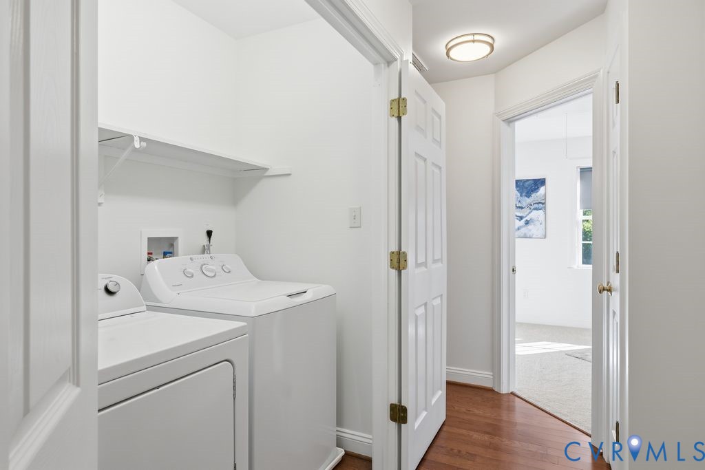 Dedicated laundry space featuring white washer and dryer hookups, overhead shelving, a flush-mount ceiling light fixture, and wood-finish flooring