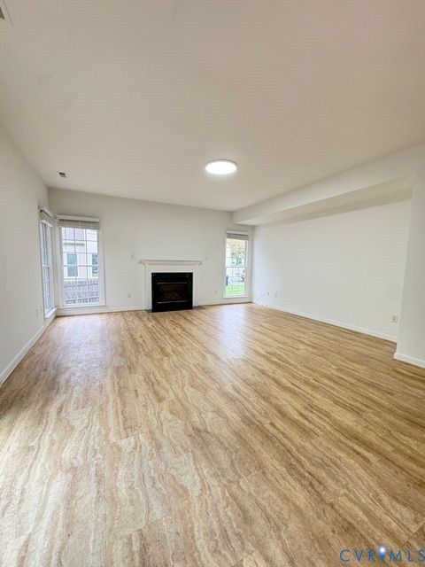 Interior space featuring wood-finish flooring, a built-in fireplace with a mantel, and multi-pane windows Interior space featuring wood-finish flooring, a built-in fireplace with a mantel, and multi-pane windows