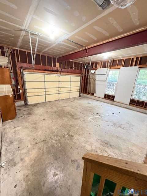 Multi-car garage featuring a concrete floor, steel support beam, overhead automatic door, and double-pane windows Multi-car garage featuring a concrete floor, steel support beam, overhead automatic door, and double-pane windows