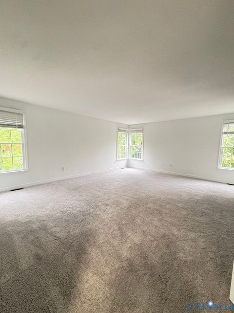 Neutral-toned carpeting, multi-pane windows, and minimalist wall finish Neutral-toned carpeting, multi-pane windows, and minimalist wall finish