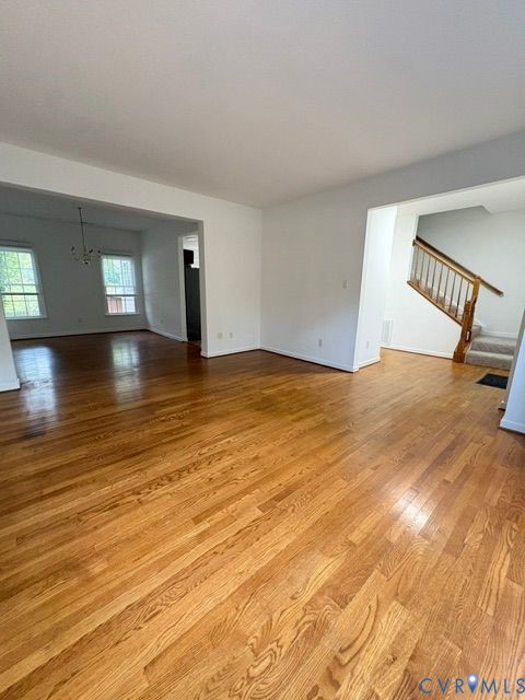 Open-concept interior featuring wood-finish flooring, staircase with wood handrails, and multi-pane windows Open-concept interior featuring wood-finish flooring, staircase with wood handrails, and multi-pane windows