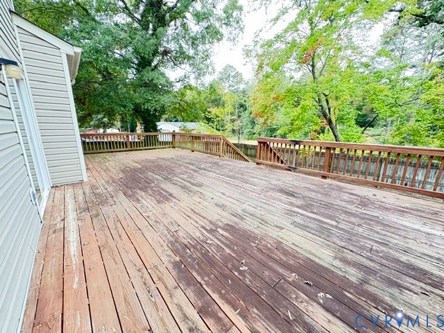 Expansive elevated wood deck featuring perimeter railings and stairs leading to the grounds Expansive elevated wood deck featuring perimeter railings and stairs leading to the grounds