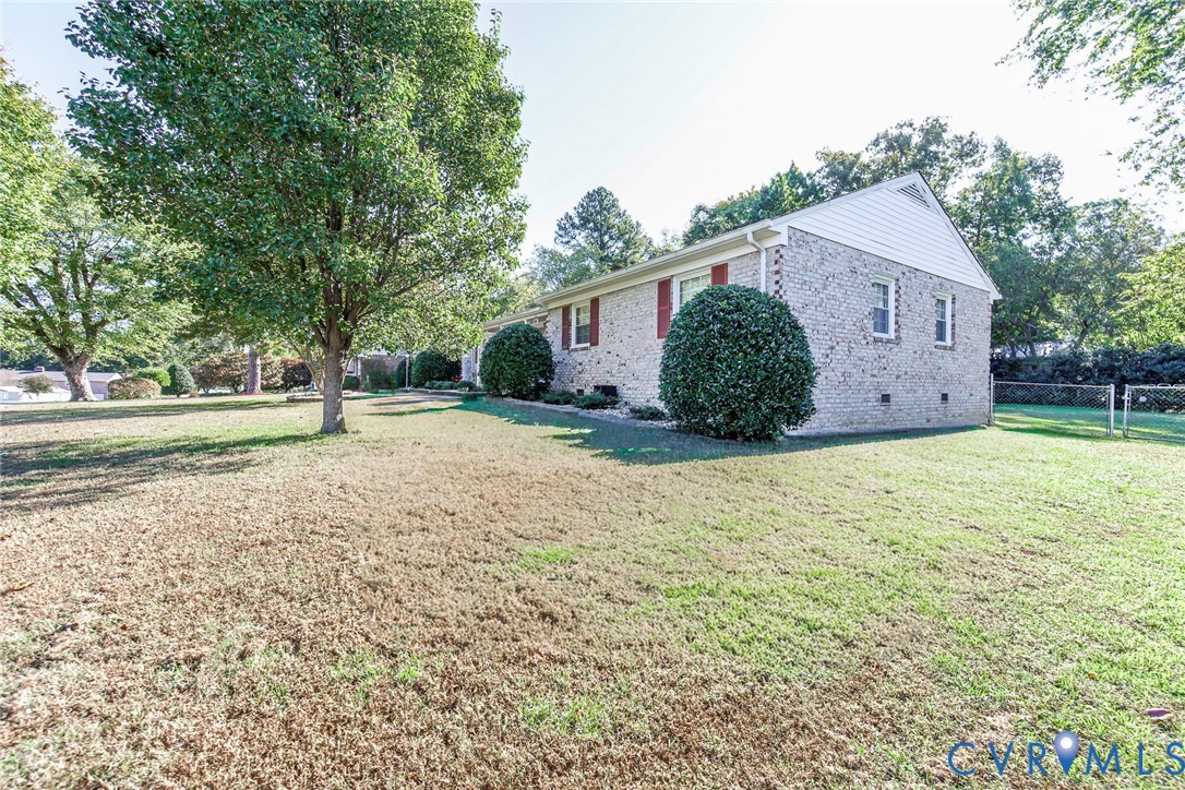 Brick exterior featuring vinyl gables, window shutters, and an expansive lawn with mature trees Brick exterior featuring vinyl gables, window shutters, and an expansive lawn with mature trees