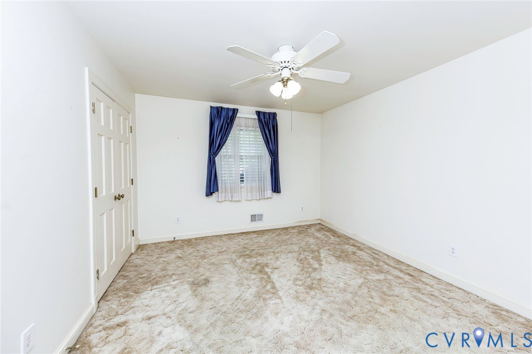 Neutral interior featuring carpeting, a multi-panel door, and a ceiling fan with integrated lighting