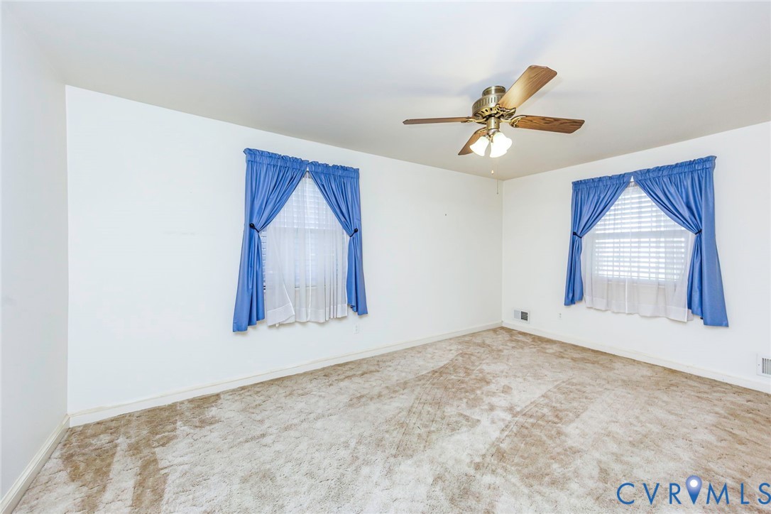 Neutral-toned wall finish, wall-to-wall carpeting, dual windows with integrated blinds, and a ceiling-mounted fan with light fixture