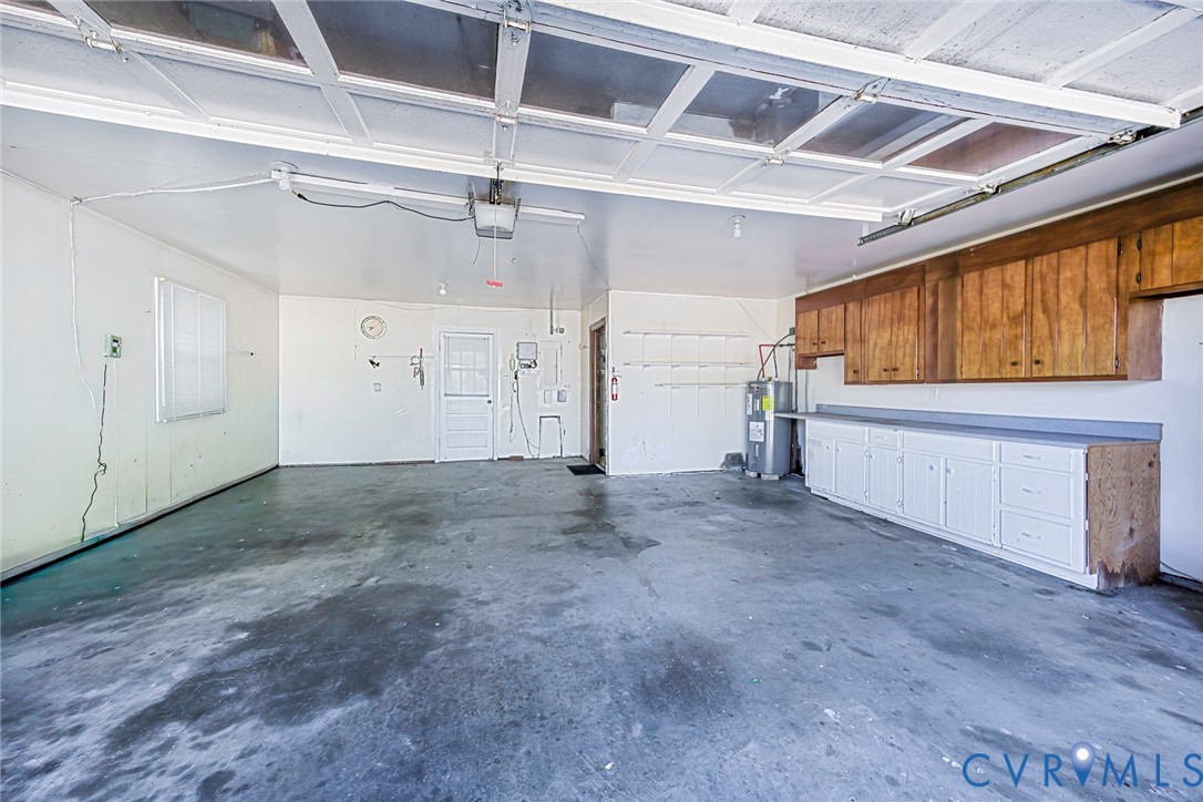 Multi-car garage featuring built-in wood cabinetry, integrated workspace countertops, and overhead garage door track system