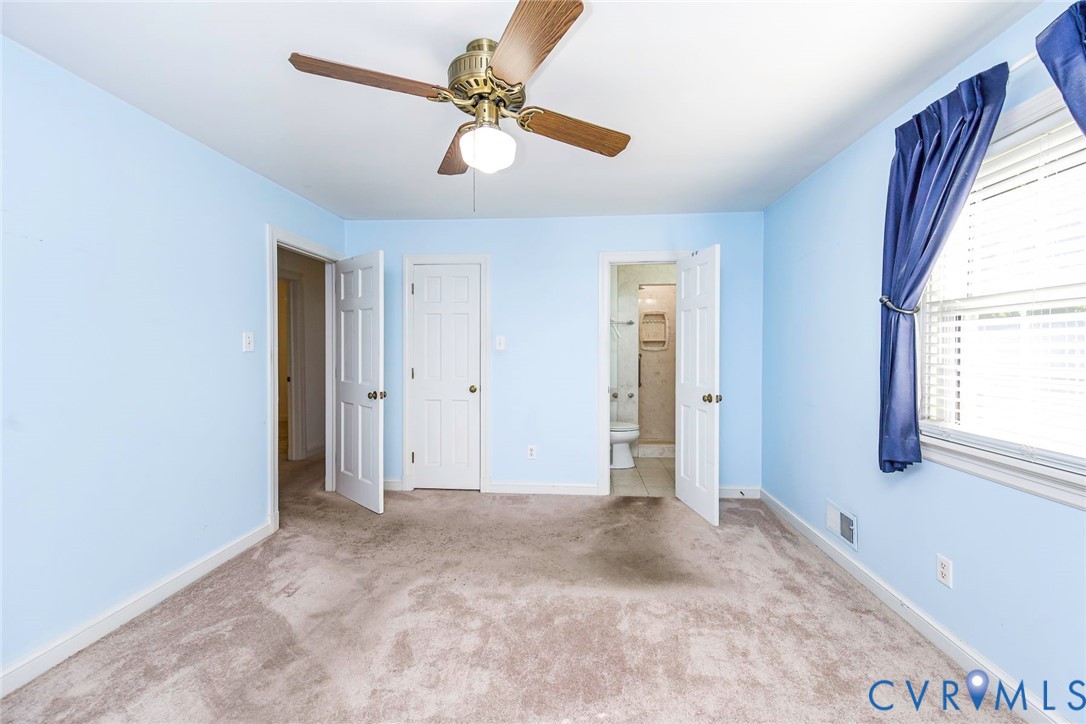 Room interior featuring wall-to-wall carpeting, a ceiling fan with integrated lighting, and multiple six-panel interior doors