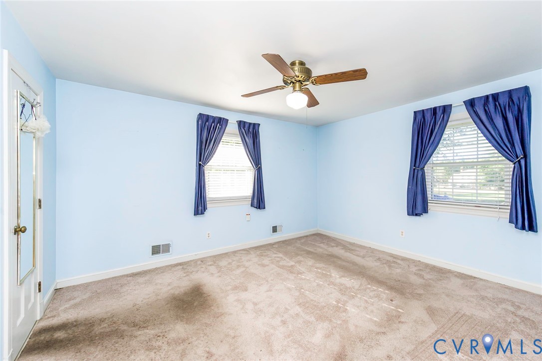 Room featuring carpeting, two windows with horizontal blinds, and a ceiling fan with integrated lighting