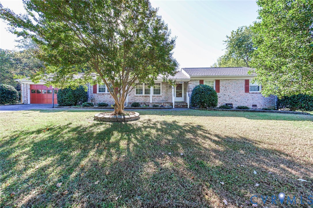 Single-story brick exterior featuring red shutters, attached garage, stone-bordered tree planter, and expansive front lawn Single-story brick exterior featuring red shutters, attached garage, stone-bordered tree planter, and expansive front lawn