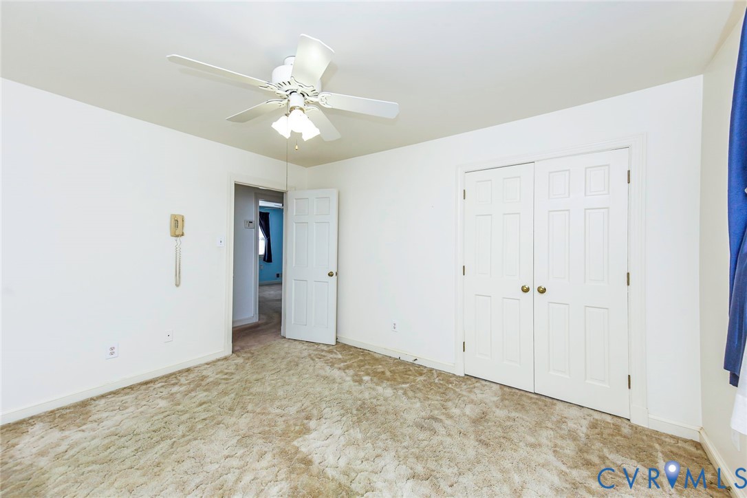 Room featuring wall-to-wall carpeting, a ceiling fan with integrated lighting, and a double-door closet