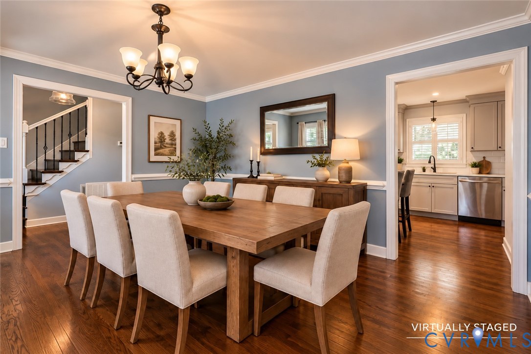 Dining room featuring wood-finish flooring, crown molding, chair rail trim, and a multi-arm chandelier