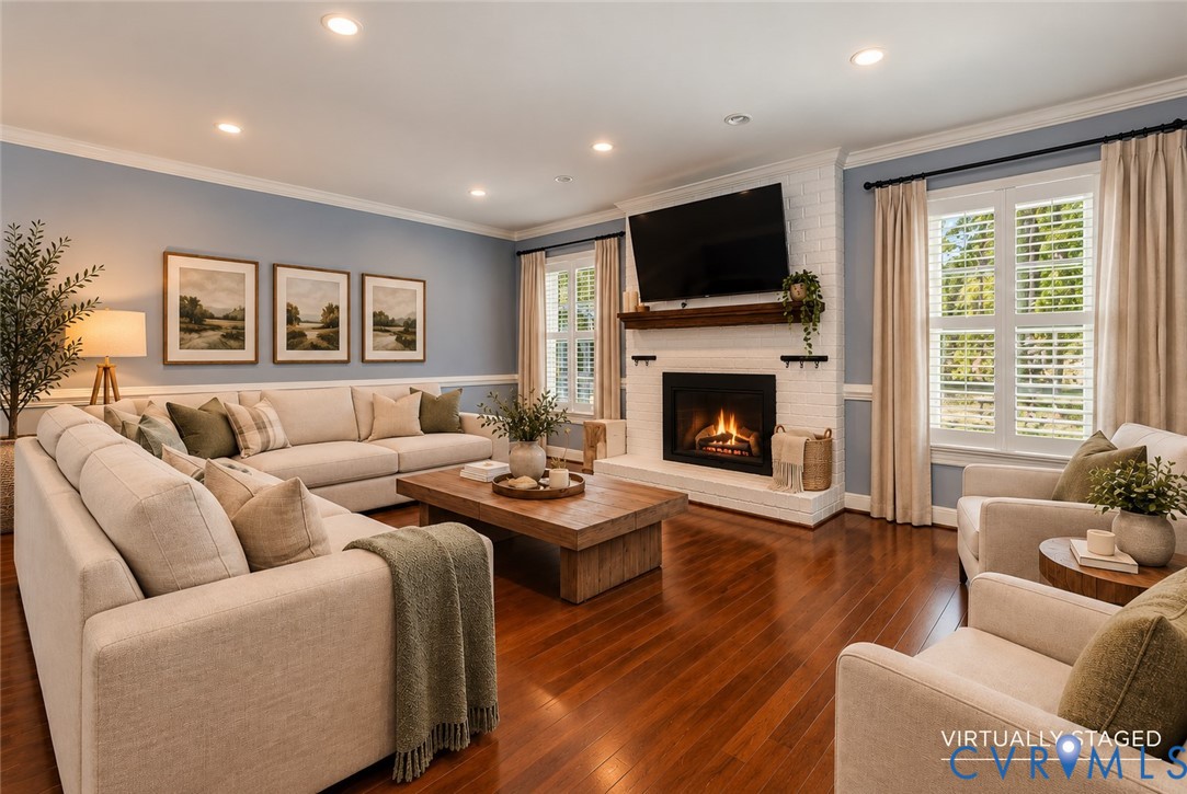 Hardwood flooring, white painted brick fireplace with a custom wood mantel, crown molding, chair rail trim, and plantation shutters