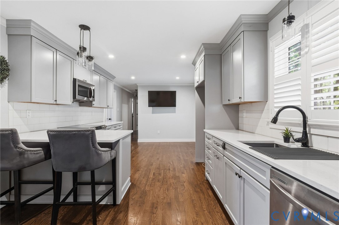 Kitchen featuring shaker-style cabinetry, white countertops, subway tile backsplash, wood-finish flooring, and a matte black gooseneck faucet