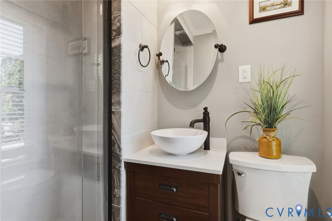 Bathroom vanity with a white composite countertop, a circular vessel sink, and a high-arc matte black faucet